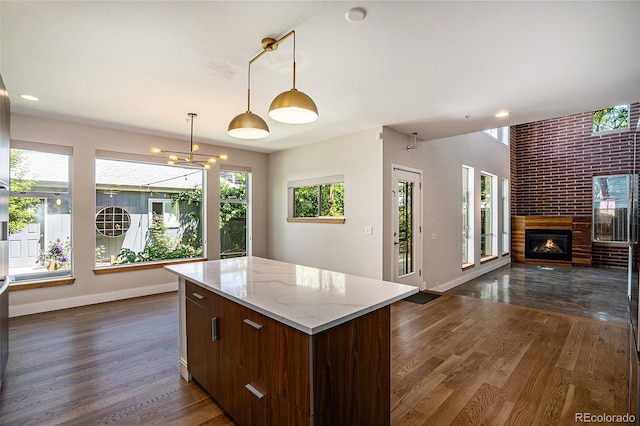 4258 Tennyson St Unit 101, Denver, CO 80212 - kitchen with open floor plan, dark wood-type flooring, a center island, a brick fireplace, and pendant lighting