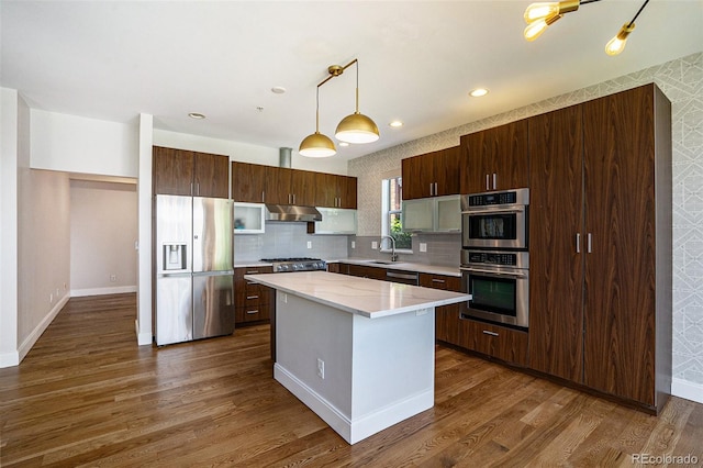 4258 Tennyson St Unit 101, Denver, CO 80212 - kitchen featuring stainless steel appliances, under cabinet range hood, light countertops, dark wood-type flooring, and a kitchen island