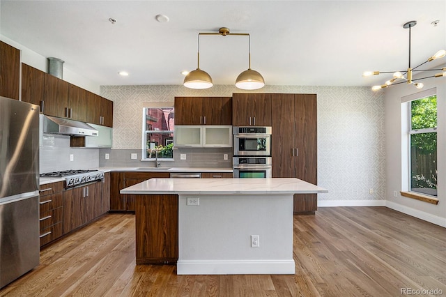 4258 Tennyson St Unit 101, Denver, CO 80212 - kitchen with appliances with stainless steel finishes, a center island, light wood finished floors, wallpapered walls, and a chandelier