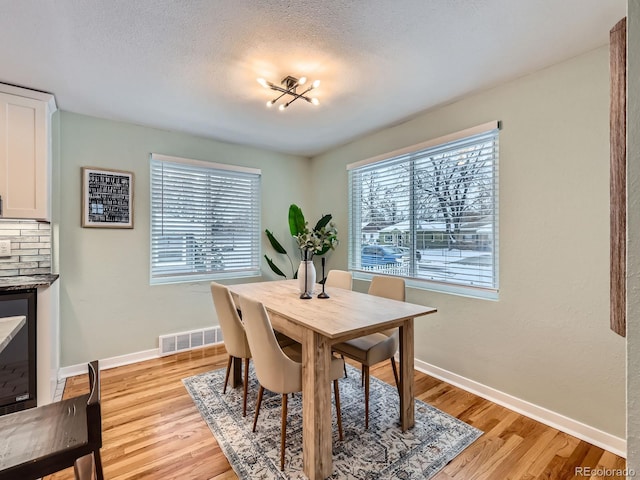 dining room with a chandelier, a textured ceiling, light hardwood / wood-style flooring, and a wealth of natural light