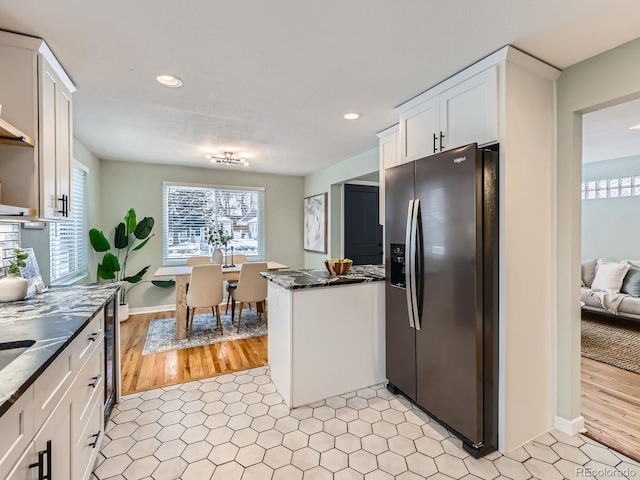 kitchen with white cabinetry, stainless steel refrigerator with ice dispenser, and dark stone counters