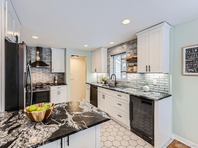 kitchen with backsplash, black appliances, wall chimney range hood, sink, and white cabinetry