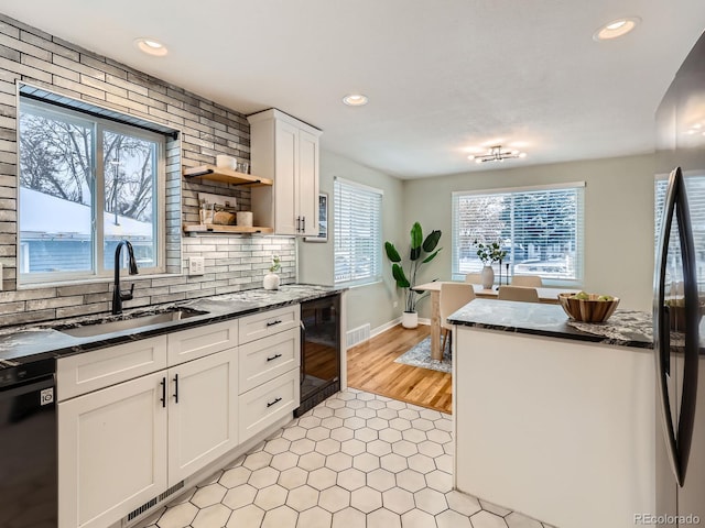 kitchen featuring white cabinets, sink, decorative backsplash, black dishwasher, and beverage cooler