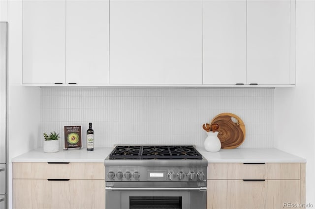 kitchen featuring decorative backsplash, modern cabinets, stainless steel stove, and light brown cabinetry