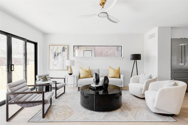 living room with visible vents, light wood-style flooring, and a ceiling fan