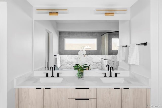 bathroom with double vanity, a marble finish shower, and a sink