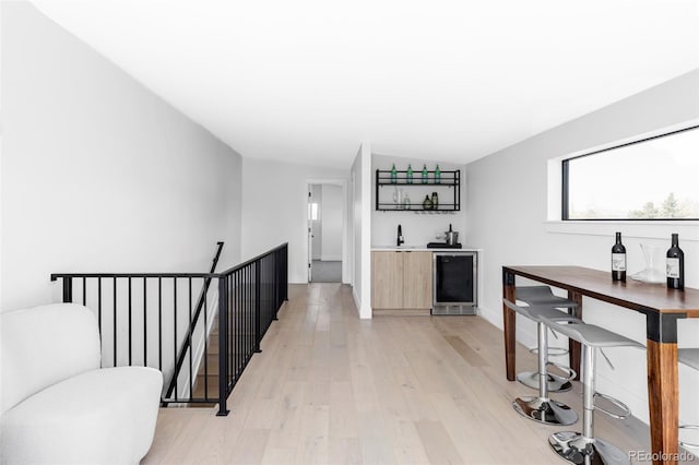 interior space featuring indoor wet bar, wine cooler, and light wood finished floors