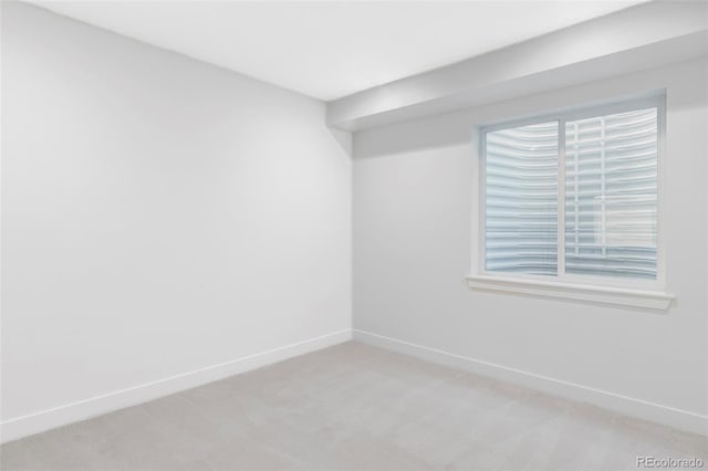 spare room with light carpet and baseboards