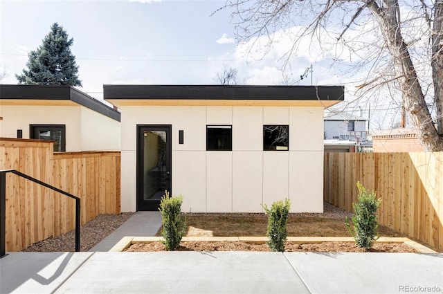 view of front of home with stucco siding, an outdoor structure, and fence