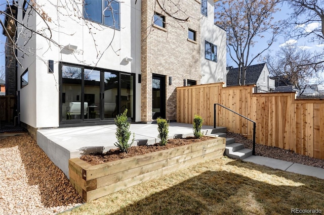 back of house featuring stucco siding, a patio, brick siding, and fence