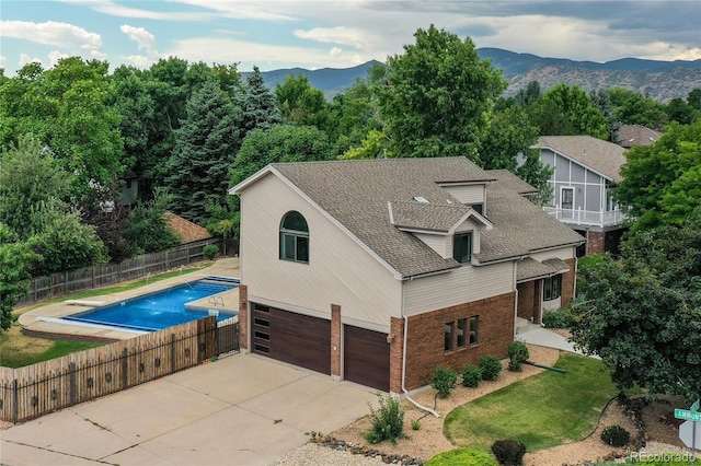 8160 W Phillips Ave, Littleton, CO 80128 - view of side of home featuring brick siding, concrete driveway, a garage, roof with shingles, and a mountain view