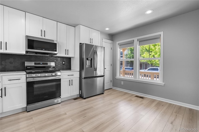 kitchen with appliances with stainless steel finishes, light countertops, white cabinets, decorative backsplash, and recessed lighting