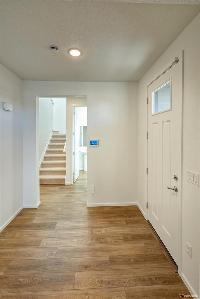 entryway featuring stairs, light wood finished floors, and baseboards