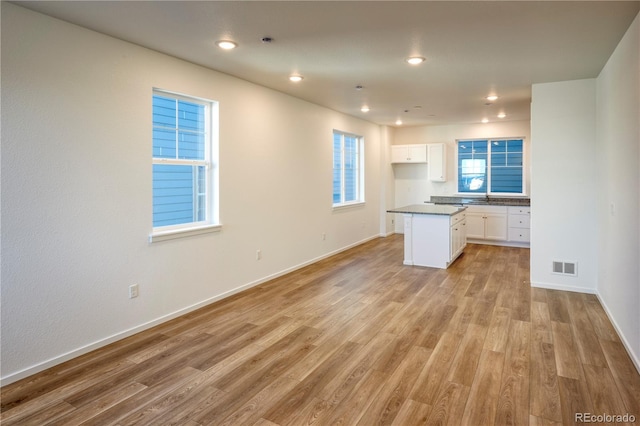 kitchen featuring white cabinets, baseboards, visible vents, and light wood-style floors