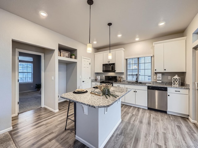 kitchen featuring a center island, decorative light fixtures, black appliances, white cabinets, and sink