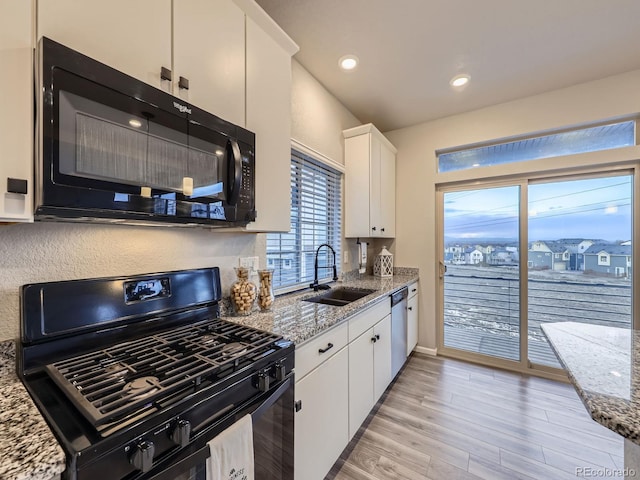 kitchen with black appliances, light hardwood / wood-style floors, light stone counters, sink, and white cabinetry