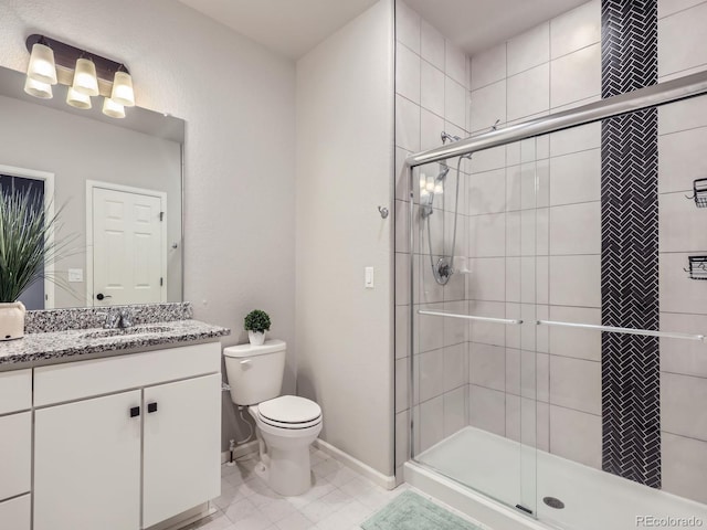 bathroom featuring toilet, a shower with shower door, and vanity