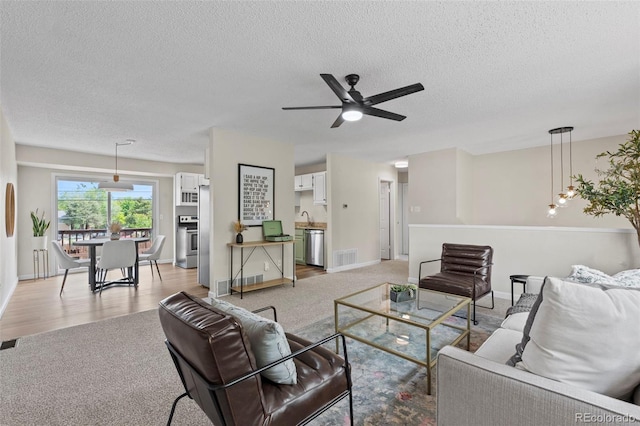 818 Don Juan Ct, Colorado Springs, CO 80909 - living room featuring light colored carpet, ceiling fan, a textured ceiling, and baseboards