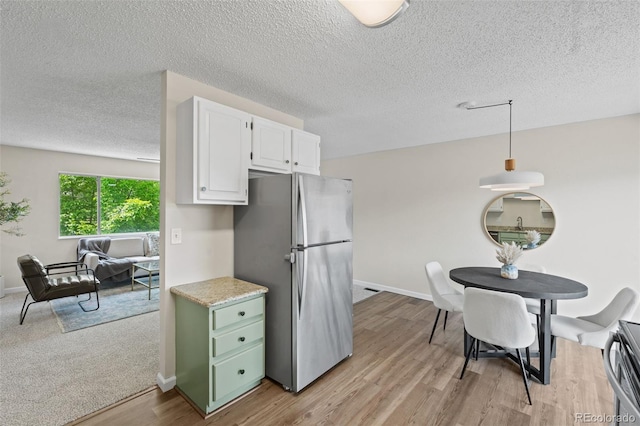 818 Don Juan Ct, Colorado Springs, CO 80909 - kitchen with freestanding refrigerator, white cabinets, light wood-style floors, a textured ceiling, and baseboards