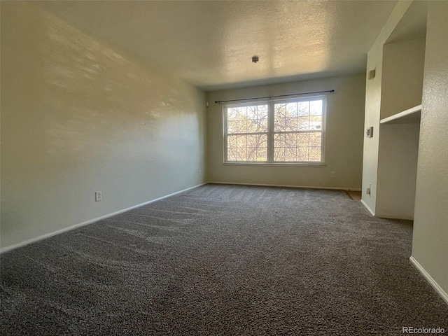 carpeted spare room featuring baseboards and a textured ceiling