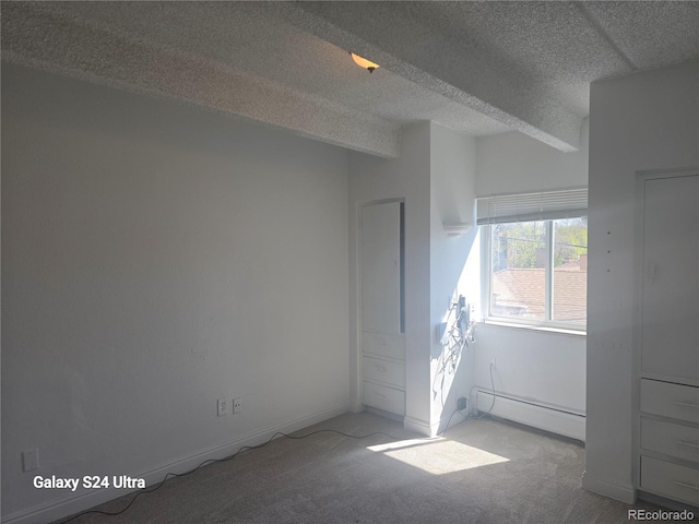 carpeted empty room with baseboards, a textured ceiling, and baseboard heating