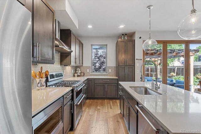 2420 S Gilpin St, Denver, CO 80210 - kitchen with appliances with stainless steel finishes, light countertops, light wood-type flooring, recessed lighting, and hanging light fixtures