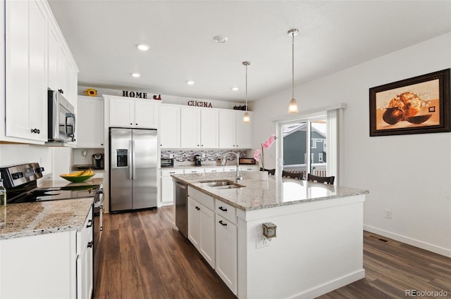 kitchen featuring pendant lighting, sink, white cabinetry, stainless steel appliances, and a center island with sink