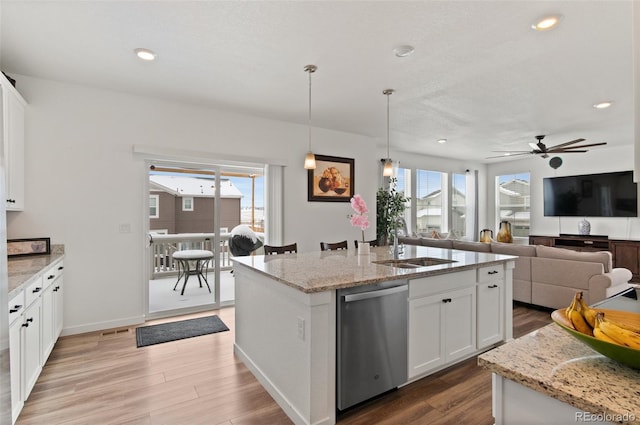 kitchen with white cabinetry, light stone counters, a kitchen island with sink, and stainless steel dishwasher