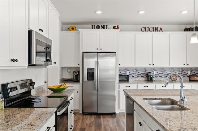 kitchen featuring appliances with stainless steel finishes, white cabinetry, sink, hanging light fixtures, and light stone countertops