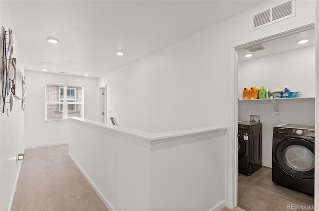 corridor featuring light carpet and washer and dryer