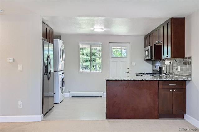 4812 W 8th Ave, Denver, CO 80204 - kitchen featuring estacked washer and dryer, baseboard heating, appliances with stainless steel finishes, a peninsula, and dark brown cabinetry