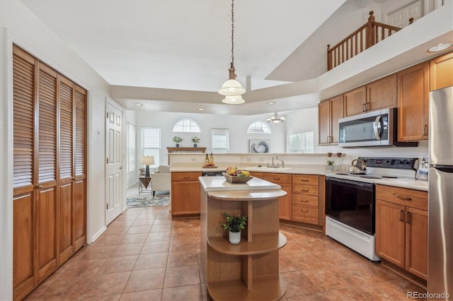 kitchen with light tile patterned flooring, sink, decorative light fixtures, a center island, and stainless steel appliances