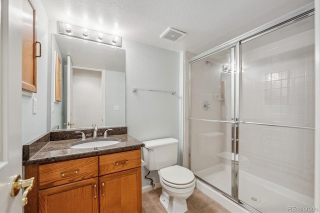 bathroom featuring vanity, a shower with shower door, tile patterned floors, and toilet