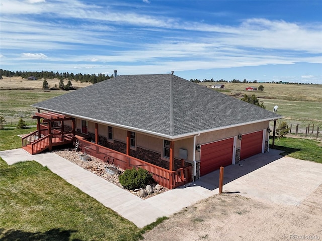 view of front of home with a porch, a rural view, a garage, and a front lawn