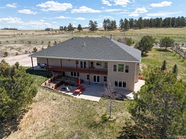 rear view of house with a patio area, a yard, a wooden deck, and a rural view