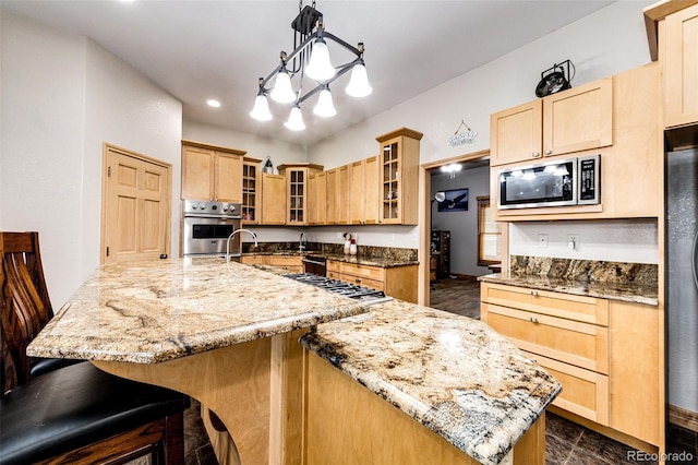 kitchen featuring light brown cabinets, light stone counters, hanging light fixtures, and appliances with stainless steel finishes