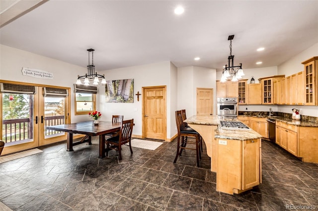 kitchen featuring a kitchen island with sink, light brown cabinetry, stainless steel appliances, and light stone counters