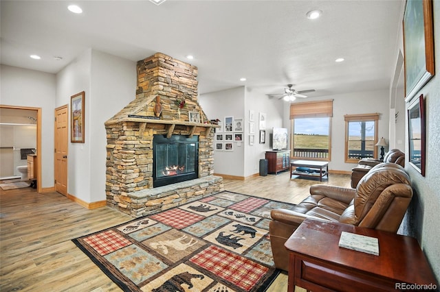 living room with ceiling fan, light hardwood / wood-style floors, and a fireplace