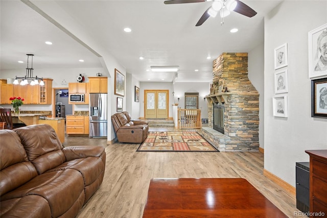 living room with ceiling fan, a fireplace, and light hardwood / wood-style floors