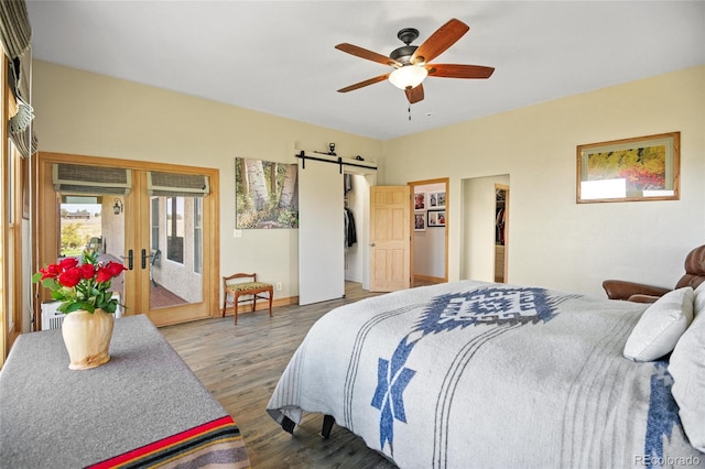 bedroom featuring french doors, a walk in closet, ceiling fan, a barn door, and hardwood / wood-style floors