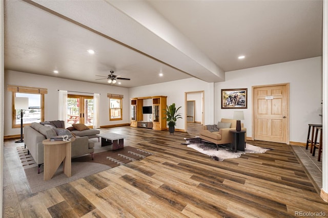 living room with hardwood / wood-style floors, ceiling fan, and beamed ceiling