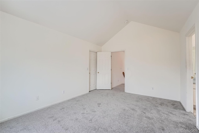 carpeted spare room with vaulted ceiling