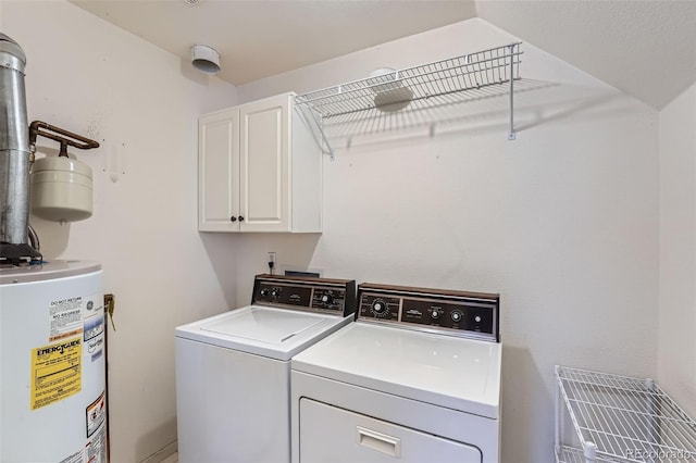 clothes washing area featuring gas water heater, cabinets, and washer and dryer