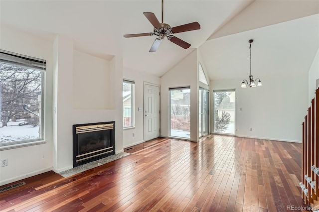 unfurnished living room featuring hardwood / wood-style floors, ceiling fan with notable chandelier, and lofted ceiling