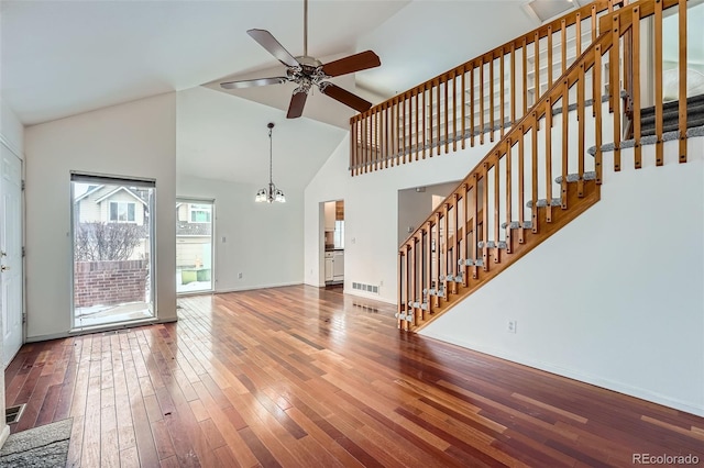 unfurnished living room featuring hardwood / wood-style flooring, ceiling fan with notable chandelier, and high vaulted ceiling