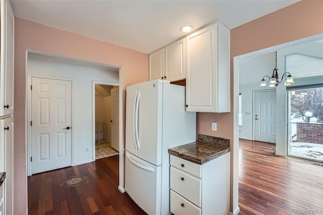 kitchen with hanging light fixtures, dark hardwood / wood-style flooring, white cabinets, an inviting chandelier, and white fridge