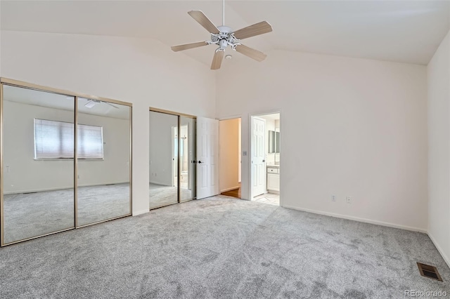 unfurnished bedroom with multiple closets, ceiling fan, light colored carpet, high vaulted ceiling, and connected bathroom