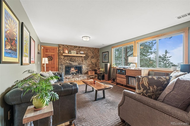 2857 Hiwan Dr, Evergreen, CO 80439 - living area with wood finished floors, a stone fireplace, and visible vents