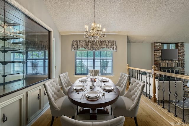 8164 Flower Cir, Arvada, CO 80005 - dining space featuring a textured ceiling, a chandelier, wood finished floors, and a fireplace