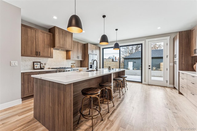 kitchen featuring tasteful backsplash, light hardwood / wood-style flooring, a spacious island, decorative light fixtures, and a breakfast bar